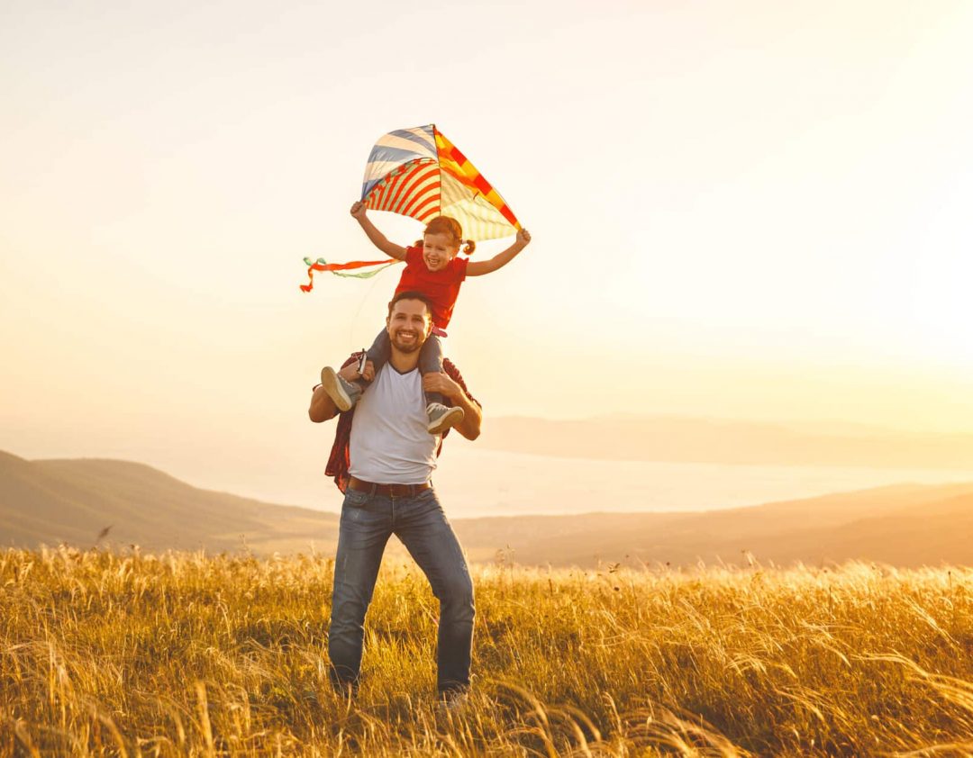 famiglia felice padre e figlia corrono con un aquilone su un prato